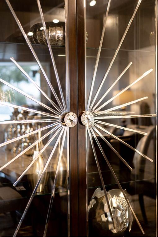 A cabinet with clear doors with a star like design coming from the door knobs