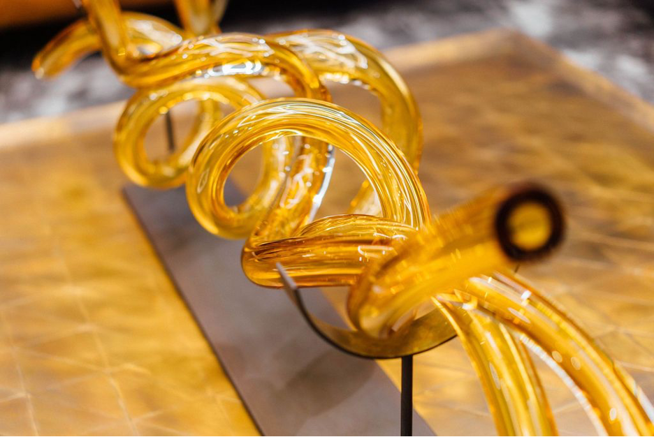 Yellow, glass blown rods that are twisting around eachother
